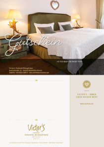 Ein Doppelbett, über dessen Kopfteil ein kleiner herzförmiger Spiegel an der Wand angebracht ist. Links von dem Bett steht ein Nachttisch mit einer Lampe.