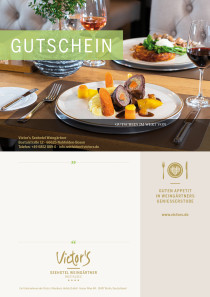 Auf einem Restauranttisch stehen zwei Teller mit appetitlich angerichteten Speisen. Daneben jeweils ein Glas mit Wein.